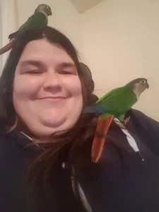 Katherine Hammond's pet conures, Charlie and Polly (with Charlie on Katherine's head).