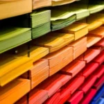 Stock image of coloured paper organised on multiple shelves of a rack.